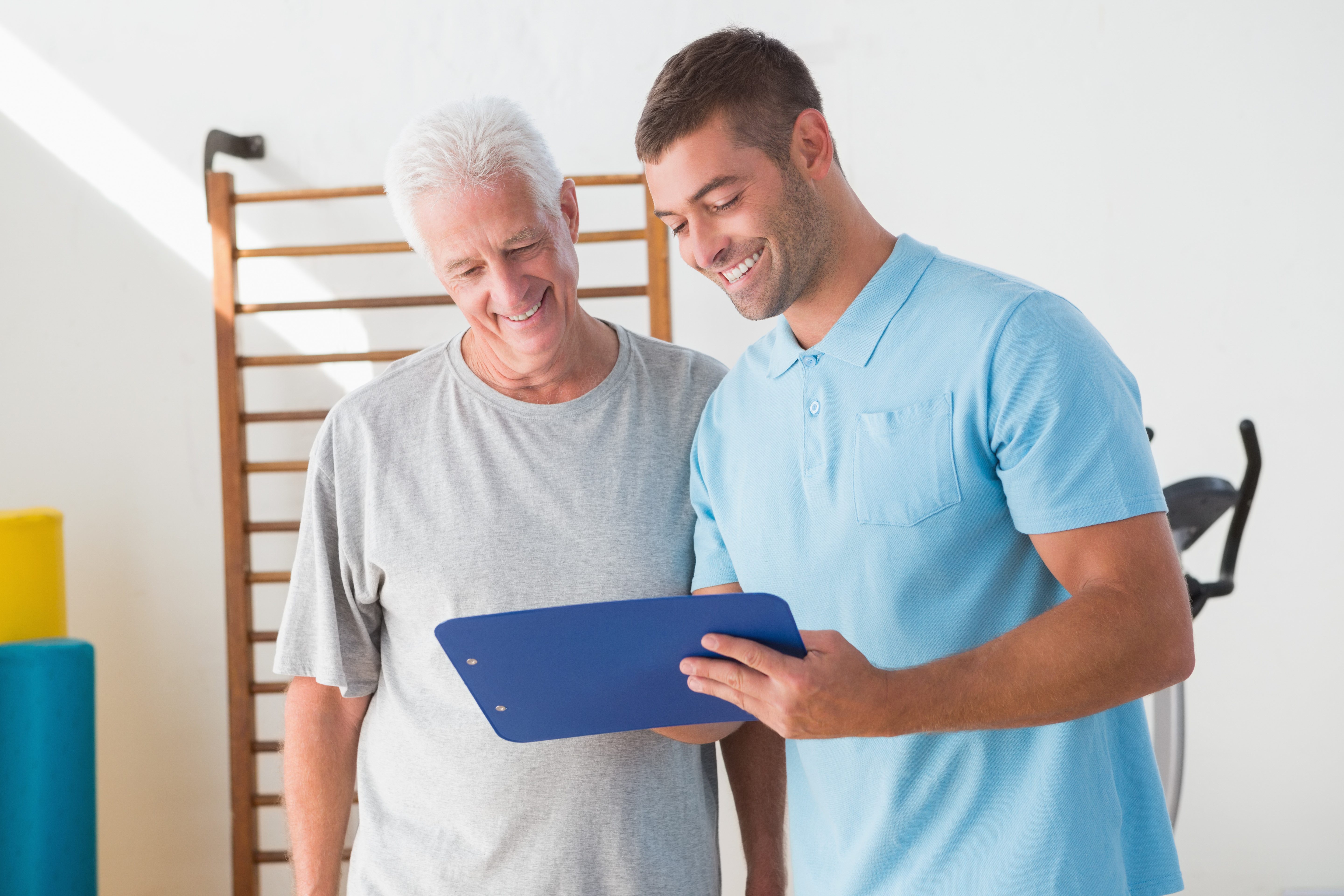 Personal Trainer taking Older Male Client through Program Card